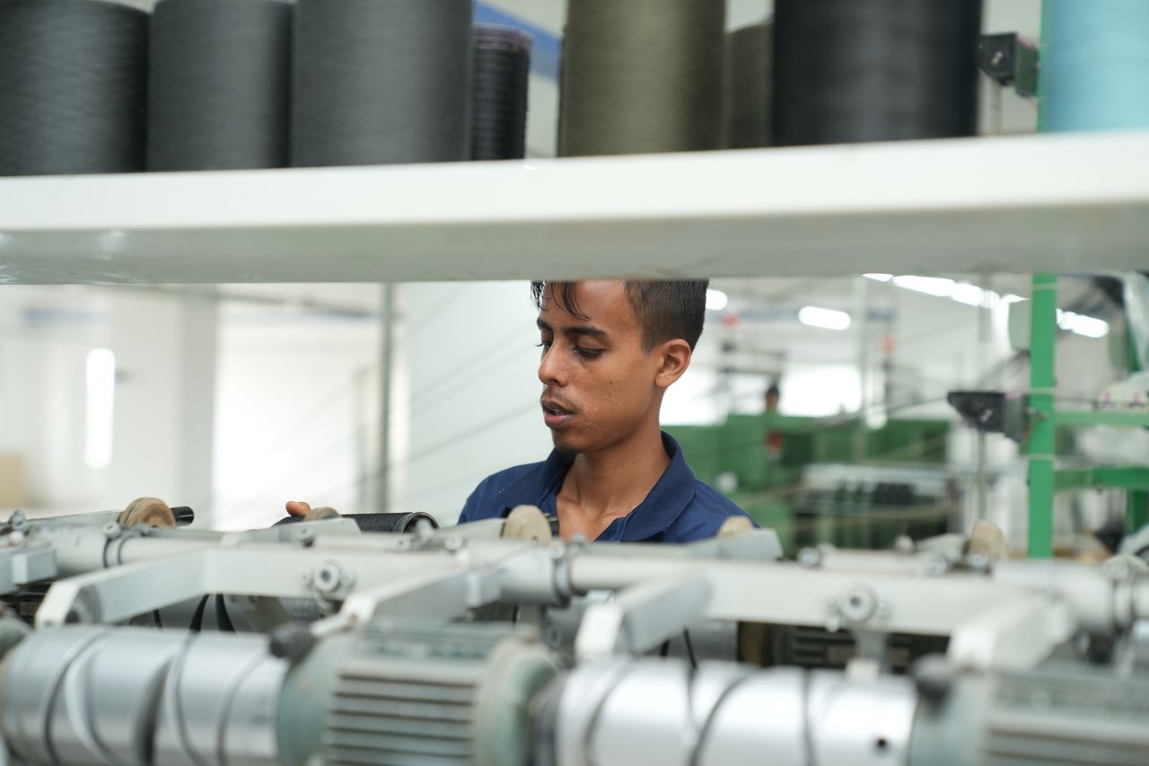 Man working on textile machinery in a modern factory setting.